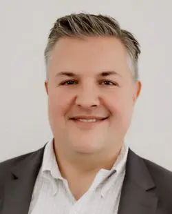 A man with spiky hair wearing a suit and smiling.