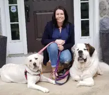 A woman sitting on the steps with two dogs.