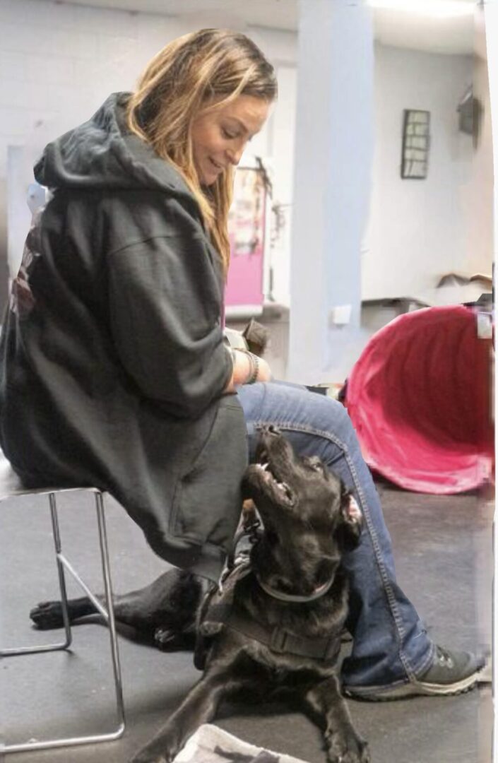 A woman sitting on top of a chair next to a dog.