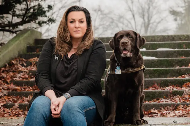 A woman sitting on steps with her dog.